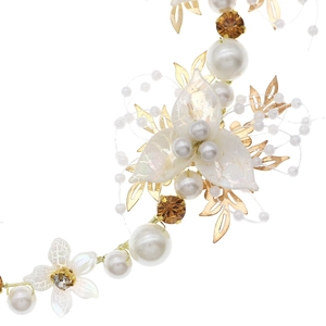 Détail de feuilles en métal doré, fleurs en acrylique blanc et perles sur le bandeau