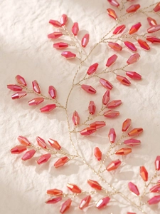 Vue macro détaillée de branches en fil doré avec perles rouges à facettes pour mariée