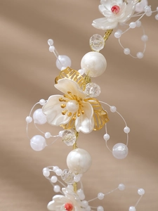 Gros plan du bandeau floral artisanal avec pétales blancs, perles et feuilles d'or