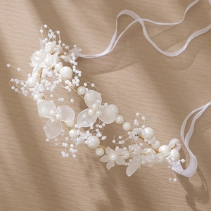 Détail d'un bandeau artisanal avec des fleurs en acrylique et des perles blanches