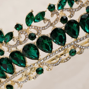 Close-up of golden bridal tiara featuring green teardrop crystals and fine rhinestones