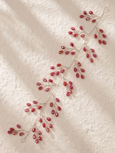 Vue détaillée d'une vigne à cheveux avec perles cristal rouge et fil doré sur pierre