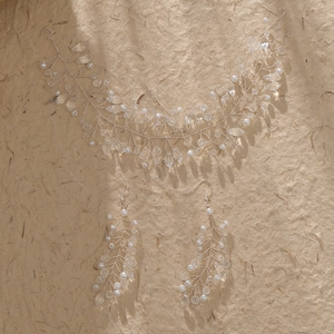Détail d'une vigne à cheveux de mariée avec perles, cristaux et boucles d'oreilles assorties