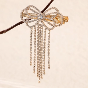 Détail d'une barrette nœud dorée avec strass brillants et élégantes franges pendantes