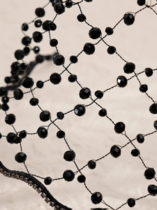 Detail of bridal black beaded mesh headpiece with crystal rhinestones on fabric base