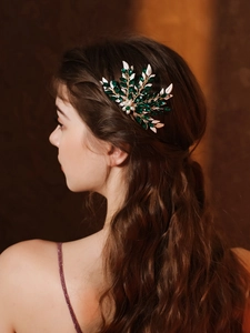 Close-up of vintage bridal hair comb with green marquise crystals and golden leaves