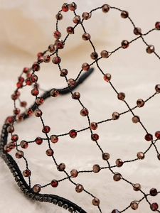 Macro detail of handmade bridal crown with red crystals and black mesh wire texture