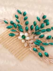 Detailed macro view of golden leaf hair comb with emerald crystals and white pearls