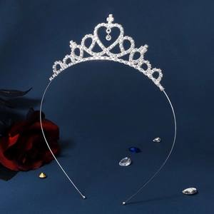 Primer plano de corona de princesa plateada con diamantes, corazón y cruz en fondo azul