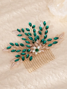 Macro detail of bridal hair comb with gold alloy leaves and green marquise rhinestones