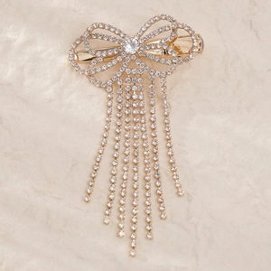 Sparkling rhinestone bow hair clip with elegant long tassels on a cream textured background