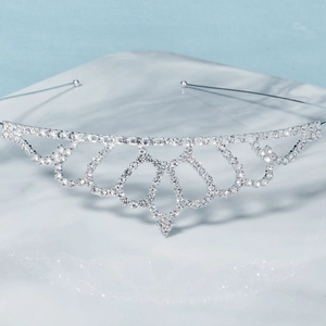 Primer plano detallado de tiara de plata con pedrería y corazones sobre mármol
