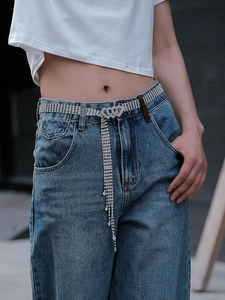 Chaîne de taille strass chic avec boucle cœur et pompon sur un jean bleu clair