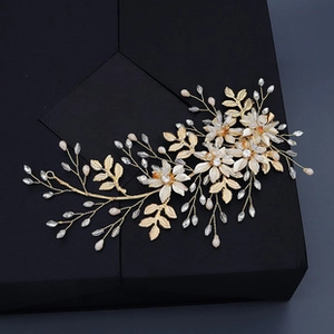 Detalle de horquilla de novia con hojas doradas y flores de resina blanca hechas a mano