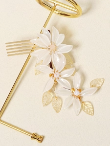 Detailed macro of crystal resin flowers and golden leaves on a bridal hair comb