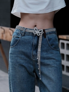 Détail de la chaîne de taille papillon en strass argentés avec franges sur un jean