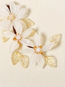 Close-up of translucent white resin flowers with pearls and golden wired leaf detail