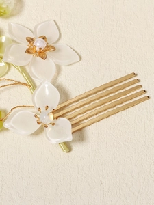 Detail view of crystal pearl hair comb with resin flowers and golden metallic base