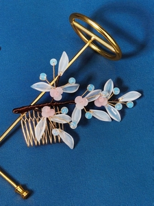 Close-up of golden bridal hair comb with pink resin flowers and crystal pearl beads