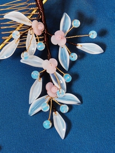 Close-up of handmade bridal hair comb with blue resin petals and copper wire weaving