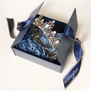 Macro shot of a vintage bronze rhinestone crown in a blue gift box with best wishes ribbon