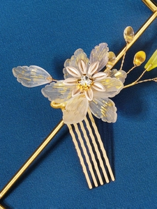 Detailed close-up of a resin flower bridal hair comb with pearls and gold wire craft