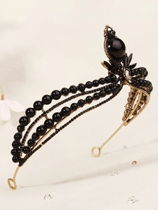 Close-up of vintage bridal crown featuring black pearls, gems, and gold metal base