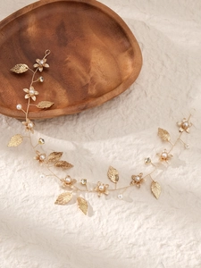 Détail d'un bandeau floral doré avec perles blanches et strass sur tissu en lin