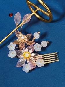 Detail of Chinese style bridal hair comb with resin flowers and pearls on blue fabric
