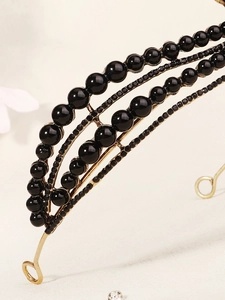 Detail of vintage gold crown with layered black beads and sparkling rhinestones