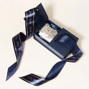 Macro shot of luxury crown jewelry in deep blue gift box with elegant silk ribbon
