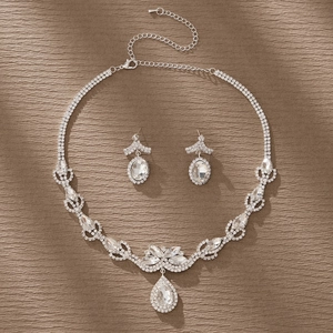 Conjunto de collar y pendientes de plata con cristales brillantes sobre fondo marrón
