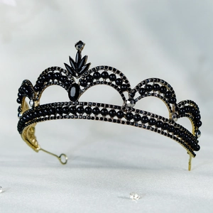 Detail of vintage black and gold bridal crown with marquise gems on white texture