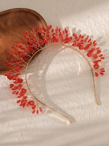 Macro shot of handcrafted gold wire headband with red crystal beads and leaf motifs