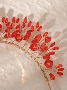 Close-up of handmade red crystal beadwork on a luxury gold wire wedding headband