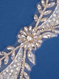 Detailed macro view of handmade gold lace applique with luxury rhinestones and crystal beads