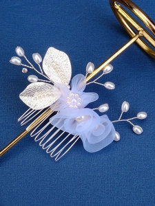 Detail of bridal hair comb with tulle flowers, pearls and golden leaves on blue backdrop