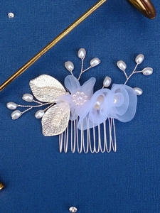 Detailed close-up of bridal hair comb with white lace flowers and golden leaves