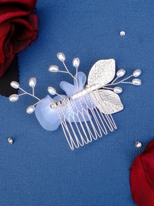 Detail of silver bridal hair comb with pearls and mesh lace on blue background