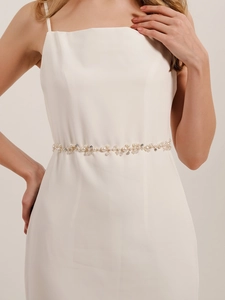 Detail of handmade pearl bridal belt with floral vine design on white dress