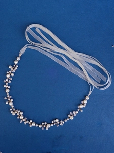 Close-up of handmade pearl and crystal bridal hair piece with delicate wire and ribbon