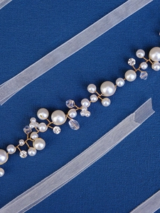 Detail of handmade bridal belt with cream pearls and crystals on gold wire