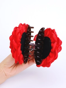 Dettaglio molletta per capelli con grande rosa rossa in tessuto e base marrone