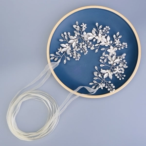 Vigne de cheveux mariée argentée avec perles et strass sur fond bleu texturé