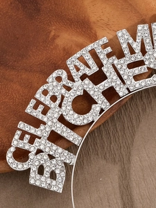 Macro view of the sparkling rhinestone CELEBRATE lettering on a metal headband