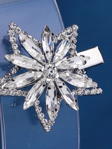 Macro detail of silver duckbill hair clip with star-shaped rhinestones and marquise crystals