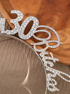 Detailed macro view of 30 & Fabulous rhinestone headband on a dark wooden base