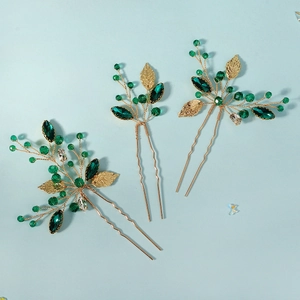 Detail of handcrafted green crystal bridal hair pins with golden metal leaf accents