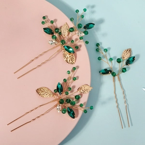 Macro detail of gold leaf hair pins with emerald rhinestones and green crystal beads