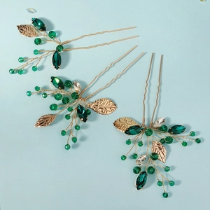 Detailed view of handmade green crystal leaf bridal hairpins with golden wire wrapping